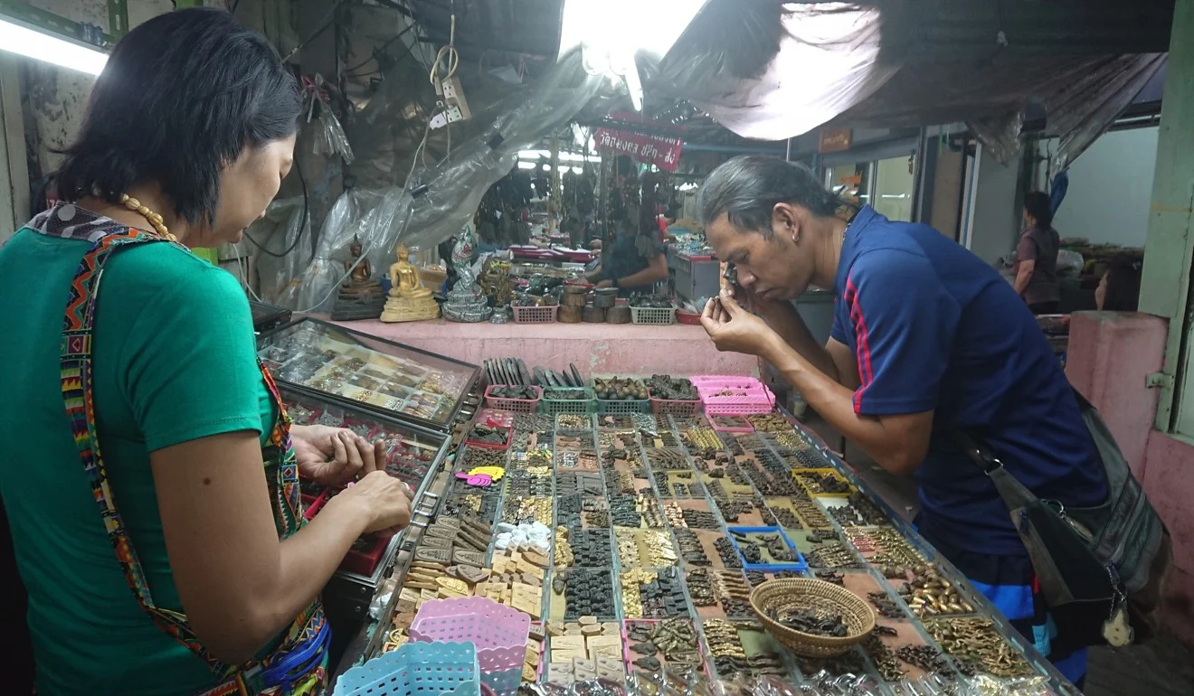 A customer inspects an amulet for sale at a Bangkok market